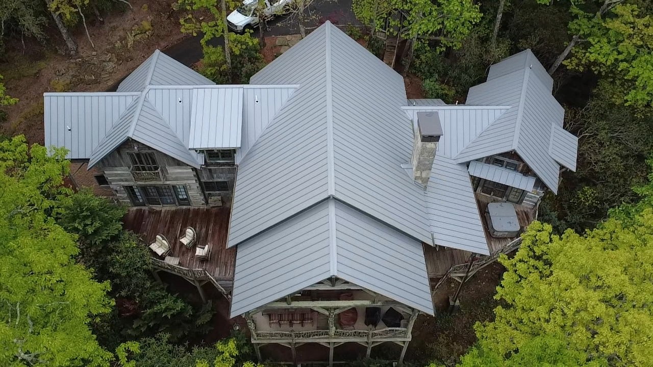 Aerial view of a timber-framed custom home with a gray metal roof
