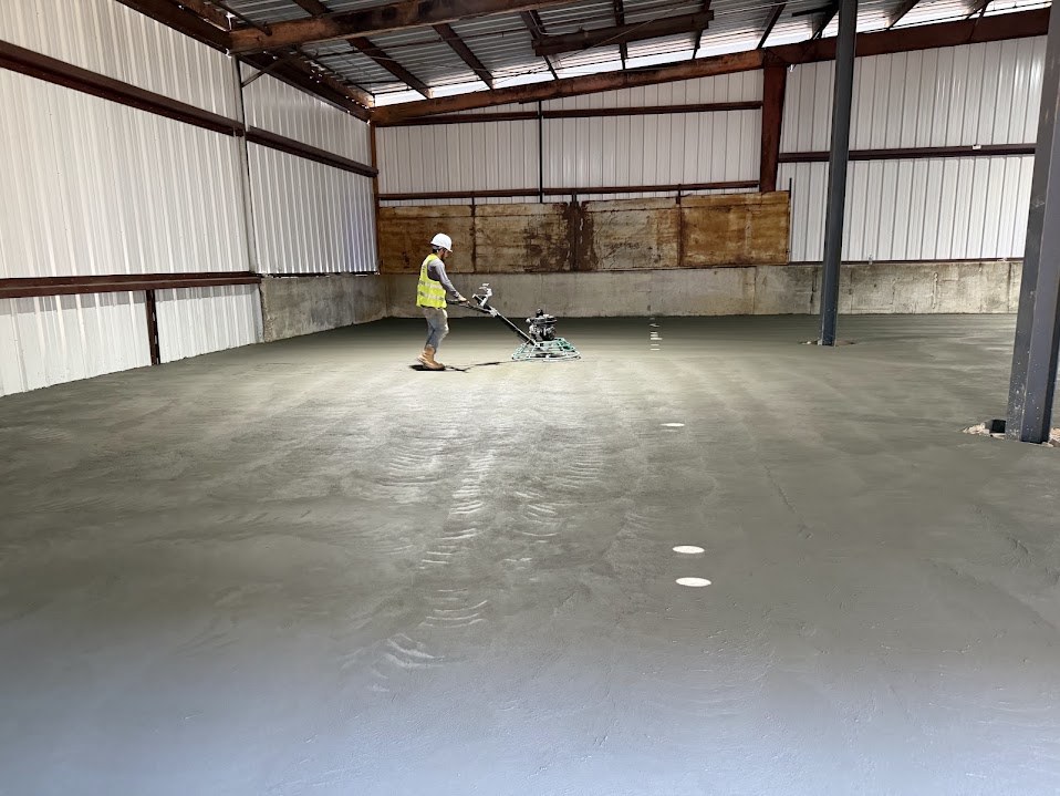Power trowel finishing a freshly poured concrete slab inside a metal building