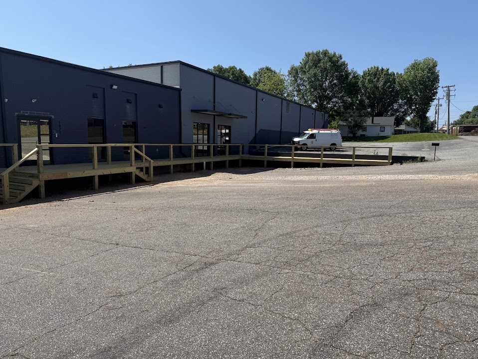 Commercial building with dark panel siding and a new wooden entry deck and ramp