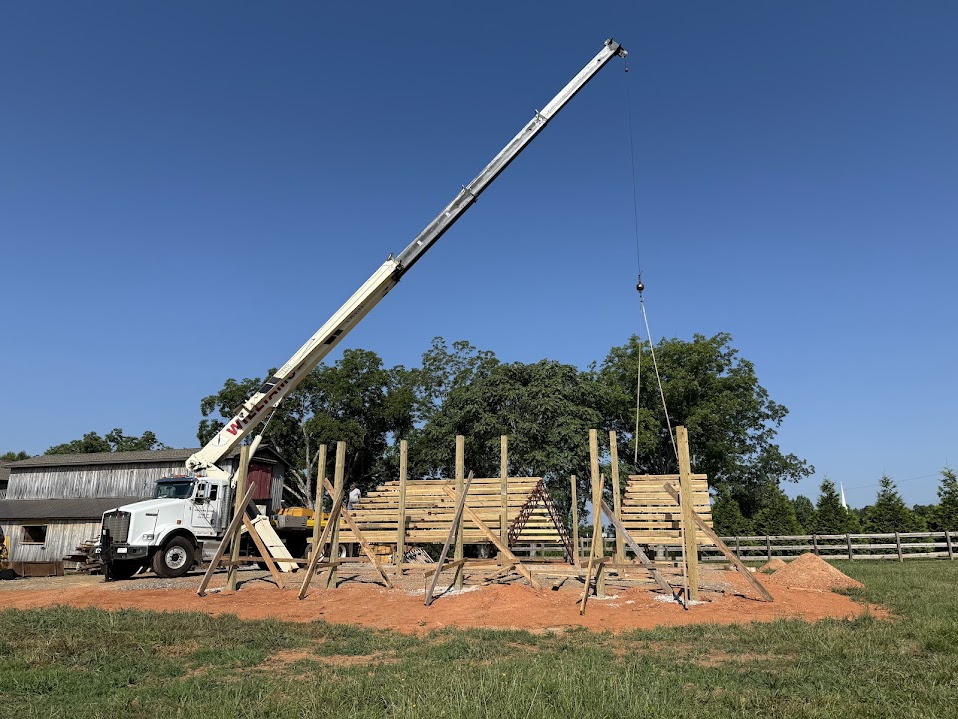 Crane truck lifting framing for a timber pavilion on a farm site