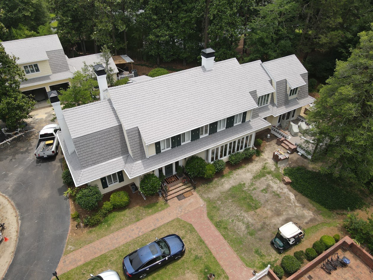 Aerial view of a large custom home with a shingle roof and landscaped grounds
