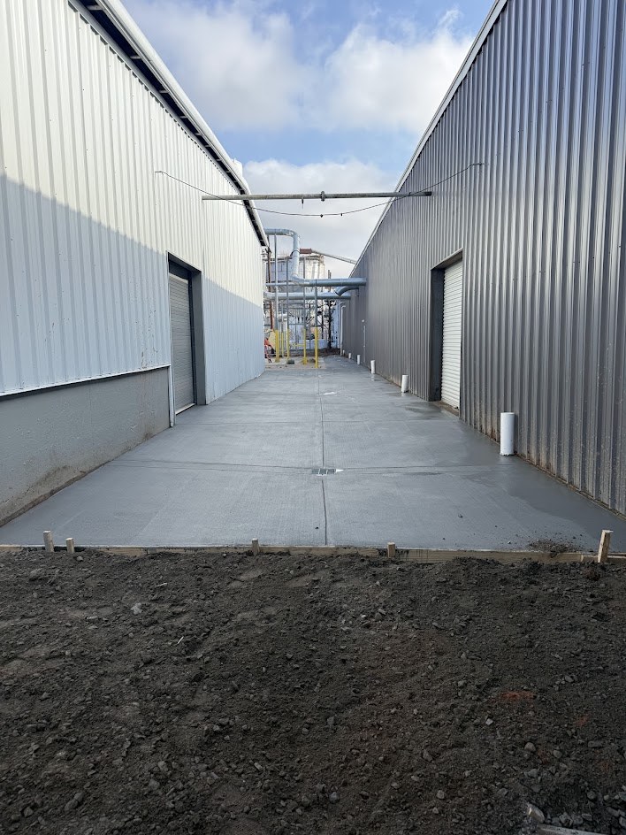 Fresh concrete drive between two metal buildings