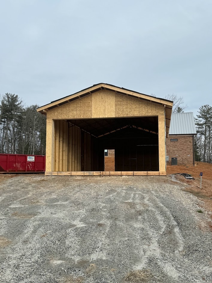 Open shed frame with OSB sheathing and a gable roof on a gravel pad