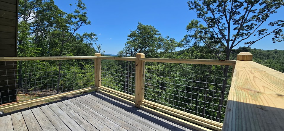 Wood deck with hog-wire mesh railings overlooking a wooded view