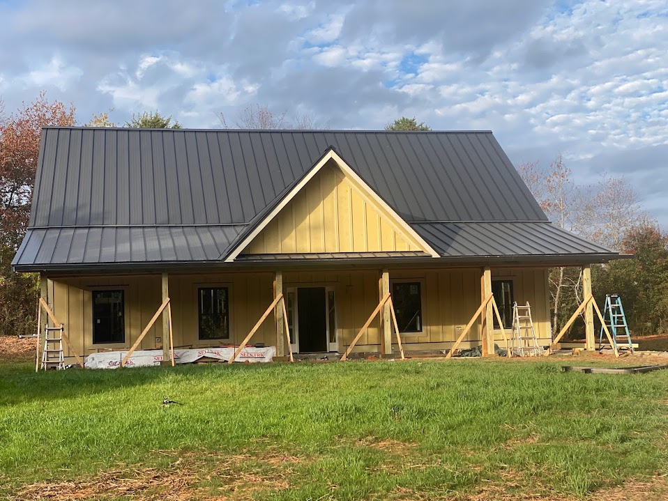 Post-frame barndominium-style home with board-and-batten siding, black trim, and a charcoal metal roof