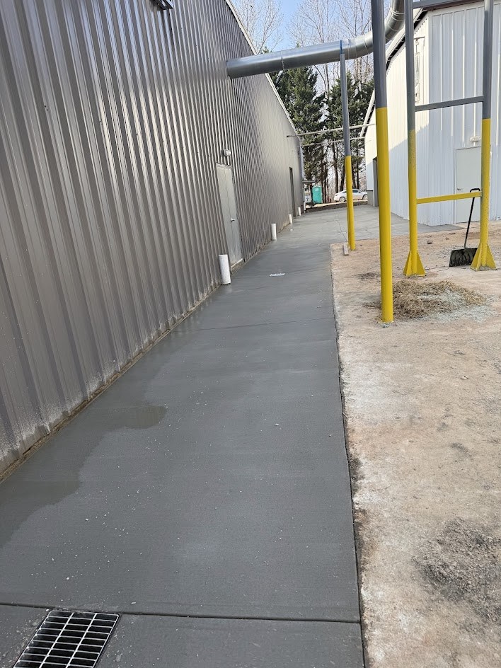 New concrete walkway along a metal building with a trench drain