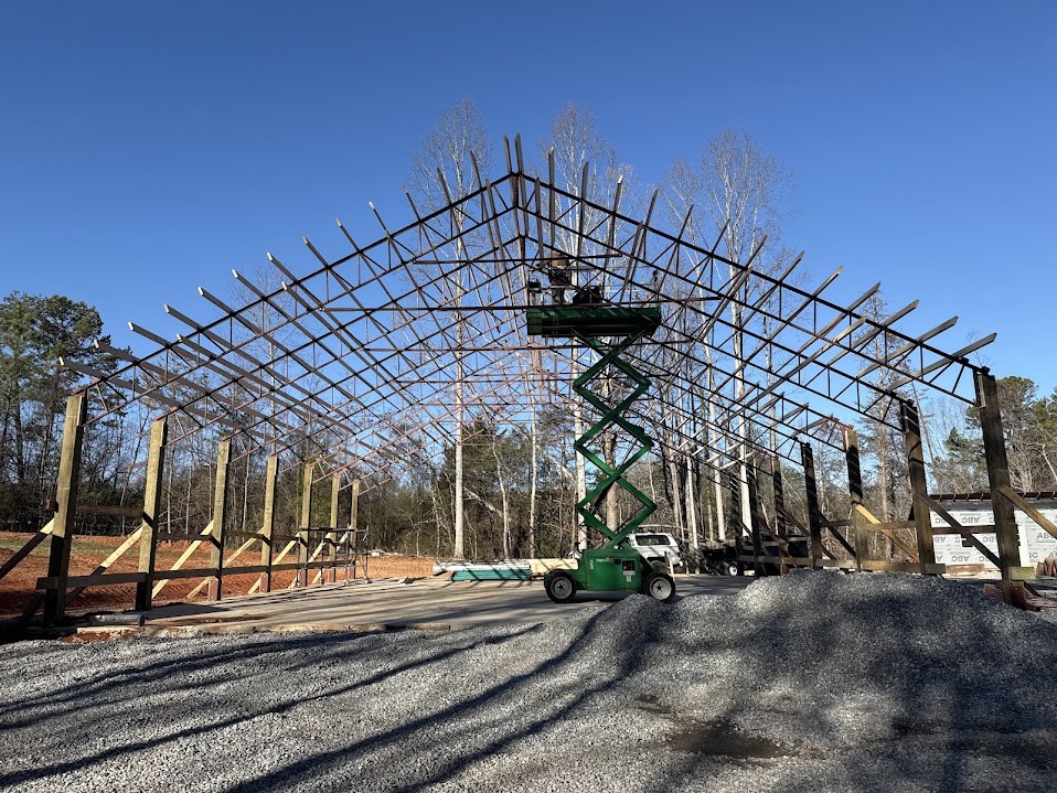 Timber posts supporting steel trusses across a wide agricultural building frame