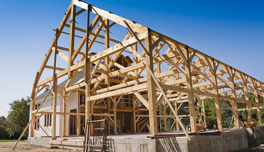 Timber frame bents with diagonal knee braces on an elevated concrete foundation