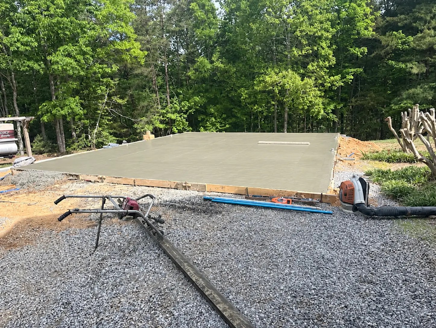 Freshly finished concrete slab foundation framed with lumber on a gravel site