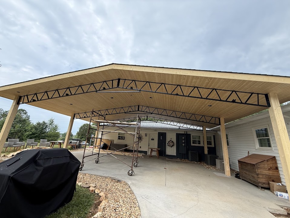 Covered patio addition with a tongue-and-groove wood ceiling and black steel trusses